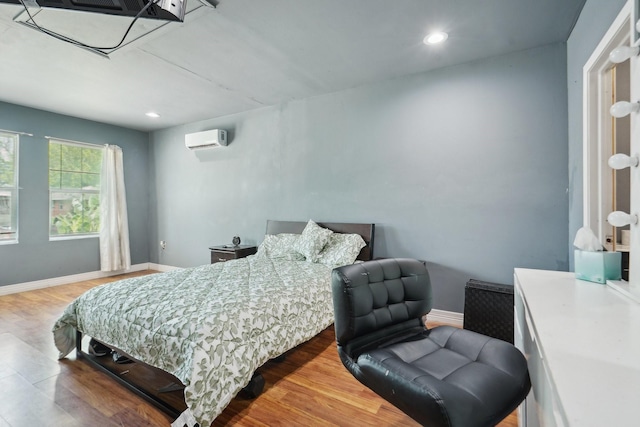 bedroom featuring baseboards, a wall mounted air conditioner, recessed lighting, and wood finished floors