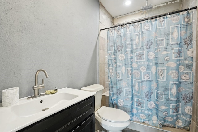 bathroom featuring vanity, curtained shower, a textured wall, and toilet