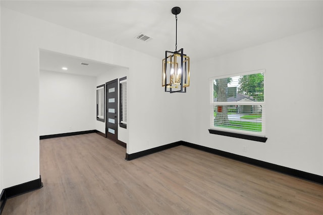 unfurnished dining area with wood finished floors, a chandelier, baseboards, and recessed lighting