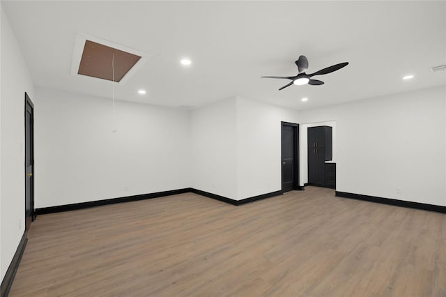 spare room featuring attic access, light wood-style flooring, baseboards, recessed lighting, and a ceiling fan