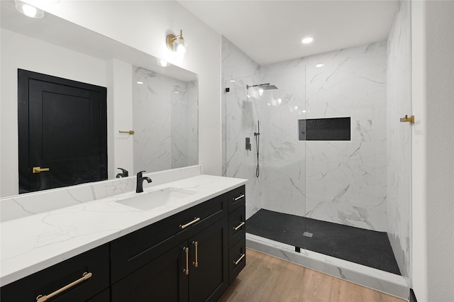 full bath with wood finished floors, a marble finish shower, vanity, and recessed lighting