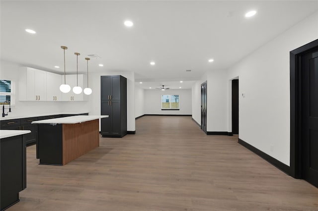 kitchen with recessed lighting, light countertops, a kitchen island, ceiling fan, and light wood finished floors