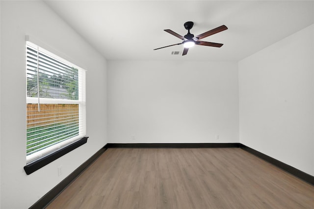 empty room with wood finished floors, a ceiling fan, and baseboards