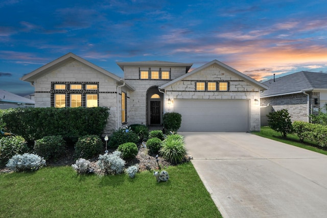 view of front of property with stone siding, an attached garage, driveway, and a lawn