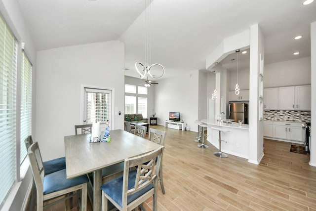 dining area featuring healthy amount of natural light, recessed lighting, a chandelier, light wood finished floors, and high vaulted ceiling