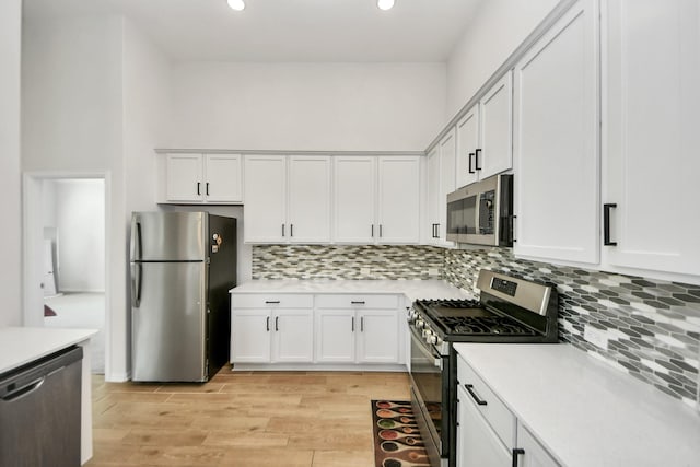 kitchen featuring appliances with stainless steel finishes, light countertops, light wood-style flooring, decorative backsplash, and recessed lighting