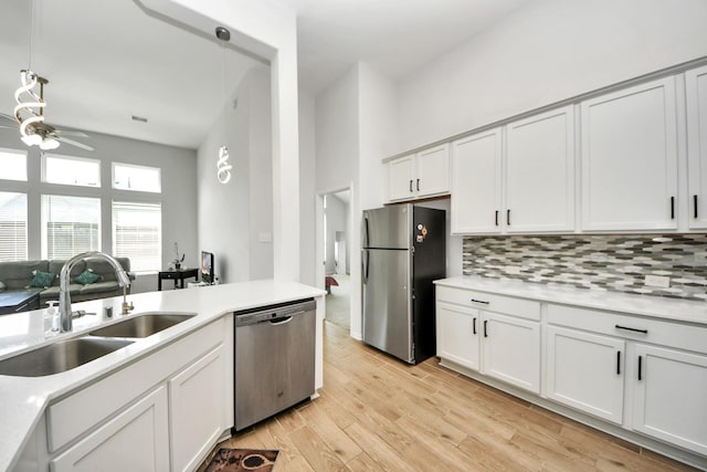 kitchen featuring stainless steel appliances, a sink, light countertops, tasteful backsplash, and ceiling fan