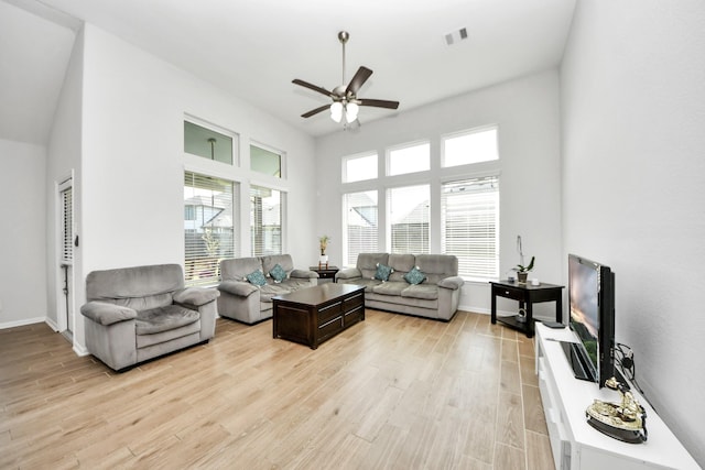 living area featuring ceiling fan, light wood-style flooring, and baseboards