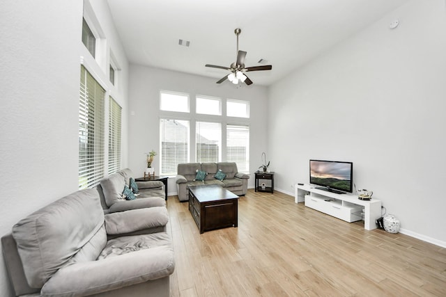 living area with a ceiling fan, light wood finished floors, and baseboards