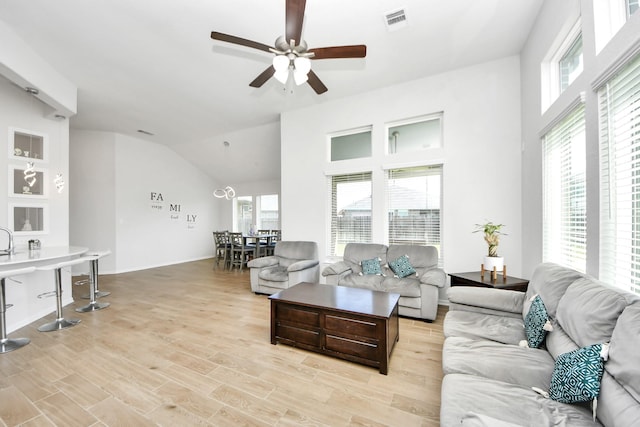 living room featuring ceiling fan, lofted ceiling, light wood-type flooring, and baseboards