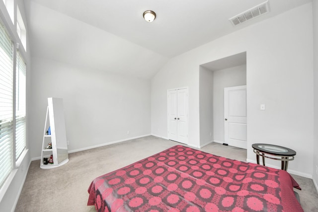 carpeted bedroom with multiple windows, vaulted ceiling, a closet, and baseboards