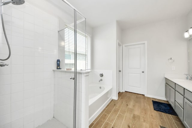 bathroom with a shower stall, a bath, wood finished floors, and vanity