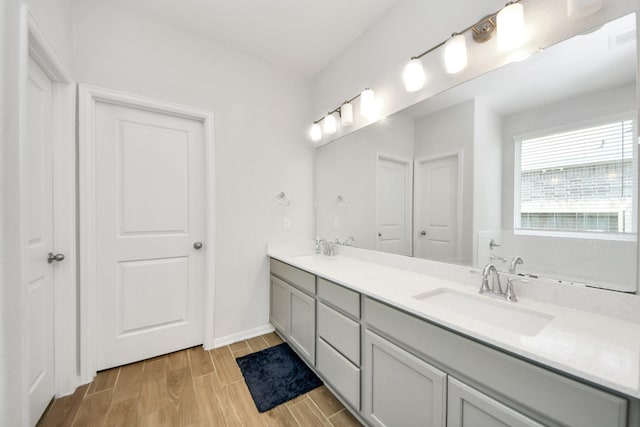 bathroom featuring wood finished floors, double vanity, and baseboards