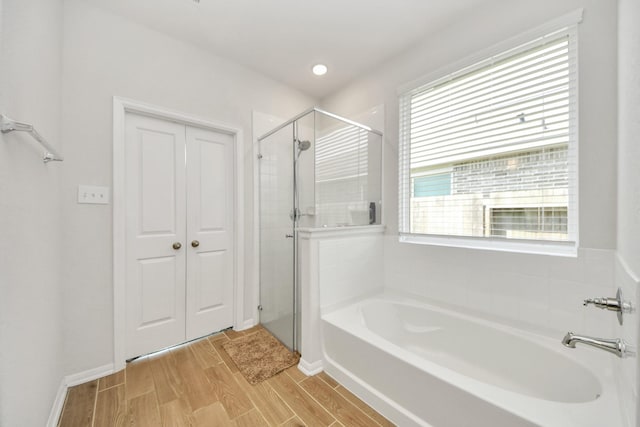 full bathroom with a bath, a shower stall, wood finished floors, and plenty of natural light