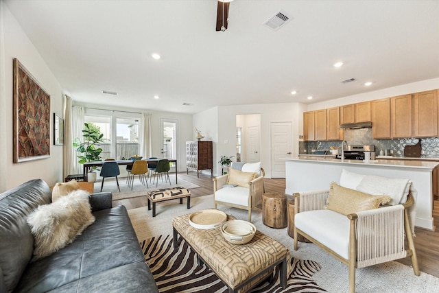 living room featuring light wood finished floors, visible vents, and recessed lighting