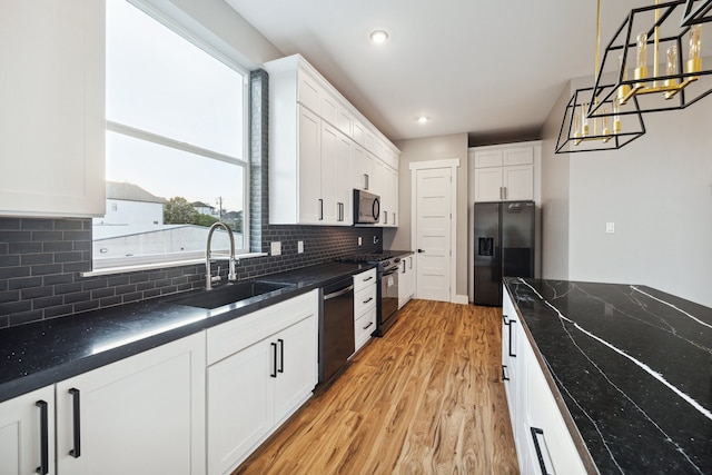 kitchen with light wood-style flooring, a sink, decorative backsplash, black appliances, and white cabinets