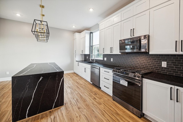 kitchen featuring a center island, baseboards, light wood finished floors, decorative backsplash, and appliances with stainless steel finishes
