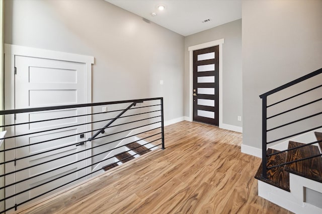 foyer with light wood finished floors, baseboards, and visible vents