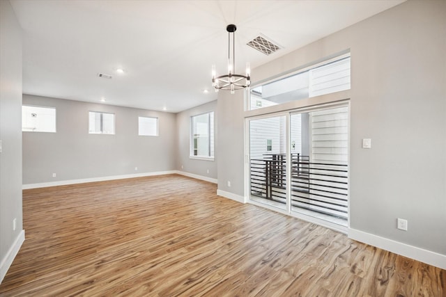 interior space with a chandelier, visible vents, wood finished floors, and baseboards