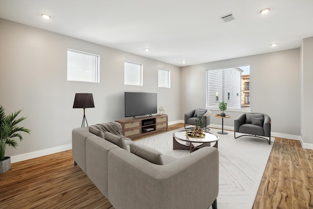 living room featuring baseboards, visible vents, and wood finished floors