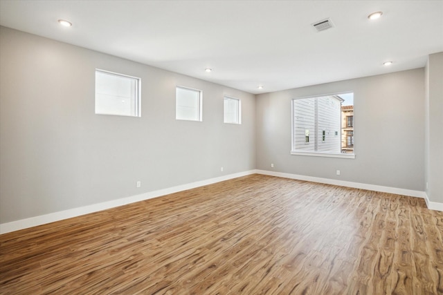 spare room featuring light wood-type flooring, visible vents, baseboards, and recessed lighting