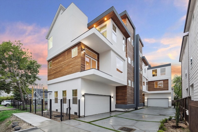 view of front of house featuring stucco siding, a garage, and fence