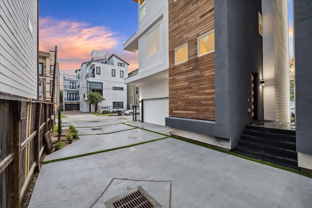 property exterior at dusk featuring concrete driveway, a garage, and fence