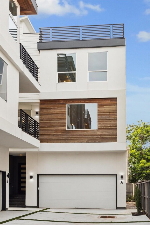 modern home featuring stucco siding, a garage, and fence