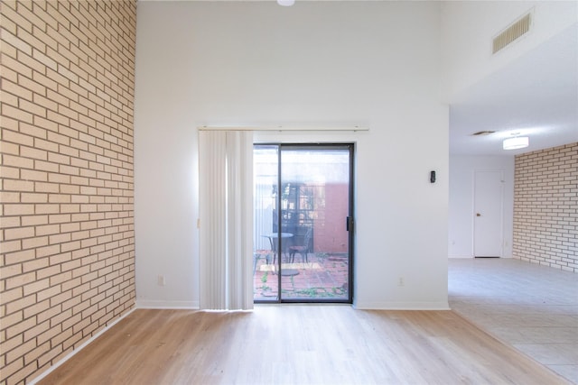 2429 Briarwest Blvd, Houston, TX 77077 - unfurnished room featuring brick wall, wood finished floors, baseboards, and a high ceiling