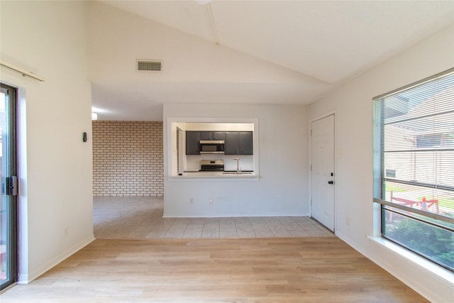 2429 Briarwest Blvd, Houston, TX 77077 - unfurnished living room with plenty of natural light, lofted ceiling, brick wall, light wood-style floors, and a sink