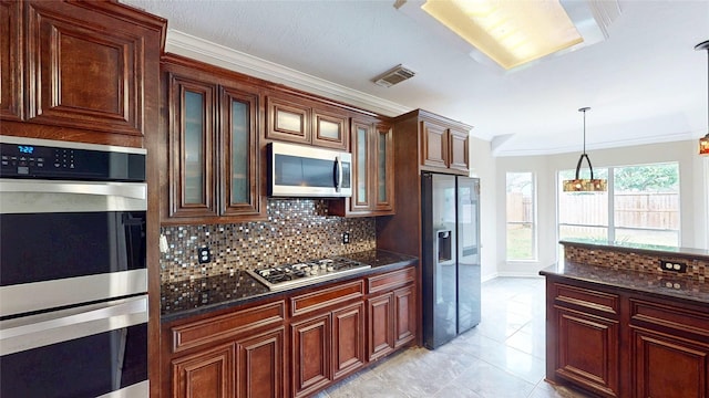 kitchen featuring stainless steel appliances, crown molding, visible vents, decorative light fixtures, and tasteful backsplash