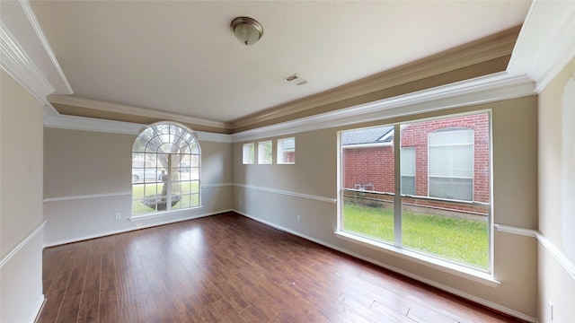 empty room featuring crown molding, baseboards, visible vents, and wood finished floors