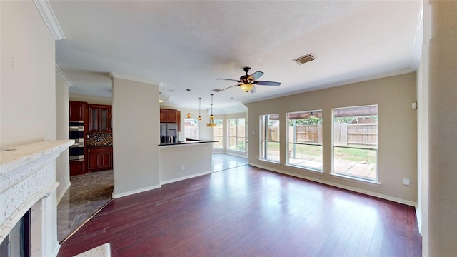 unfurnished living room featuring a ceiling fan, ornamental molding, visible vents, and dark wood-type flooring