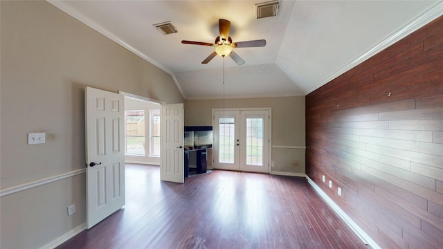 unfurnished living room with visible vents, french doors, ceiling fan, and wooden walls