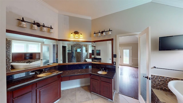 bathroom featuring crown molding, a freestanding tub, a sink, and double vanity