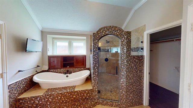 bathroom featuring a stall shower, lofted ceiling, ornamental molding, a soaking tub, and a spacious closet