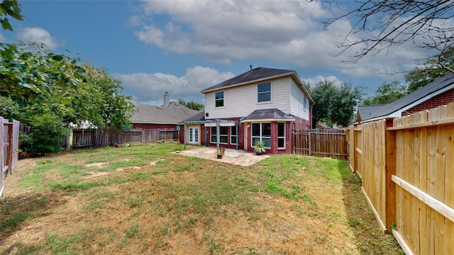 back of house with brick siding, a lawn, a fenced backyard, and a patio