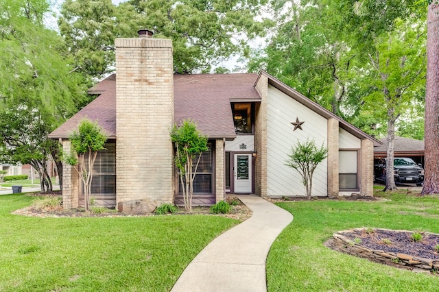 mid-century home featuring a chimney, a front yard, brick siding, and a shingled roof