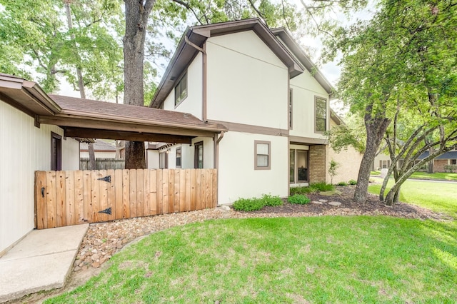 view of side of property featuring a lawn, stucco siding, brick siding, and fence