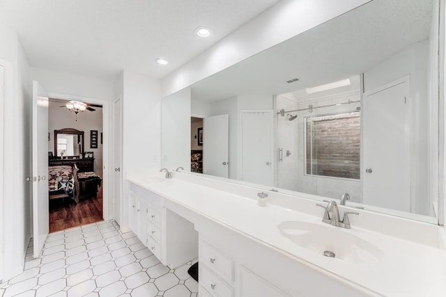 ensuite bathroom with a stall shower, double vanity, a sink, and tile patterned floors