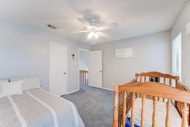 carpeted bedroom featuring baseboards, ceiling fan, visible vents, and a textured ceiling