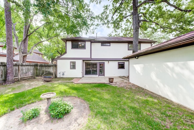 rear view of house with a lawn, a patio area, stucco siding, and a fenced backyard