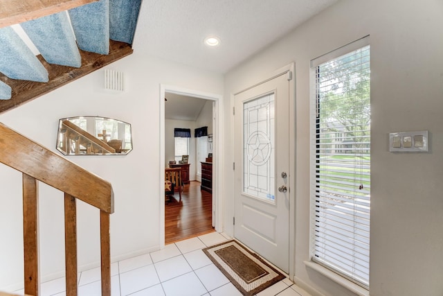 foyer entrance featuring light tile patterned floors, plenty of natural light, and baseboards