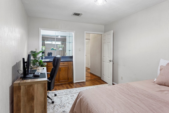 bedroom with dark wood finished floors and a desk