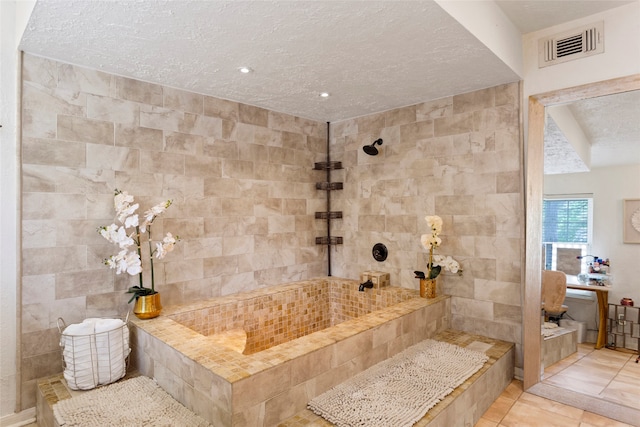 full bathroom featuring a textured ceiling, tile patterned flooring, and a tile shower