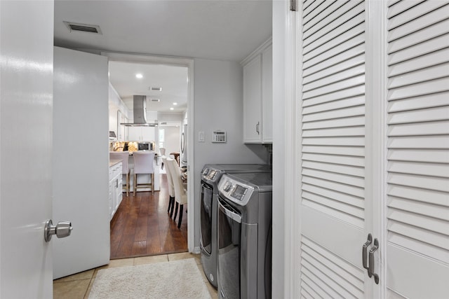 washroom with cabinet space, independent washer and dryer, light tile patterned floors, and recessed lighting