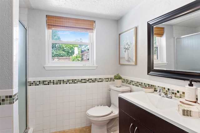 full bathroom featuring tile walls, a shower stall, a textured ceiling, toilet, and vanity