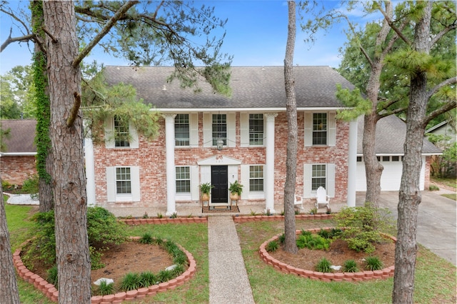 neoclassical home with a shingled roof, concrete driveway, brick siding, and an attached garage