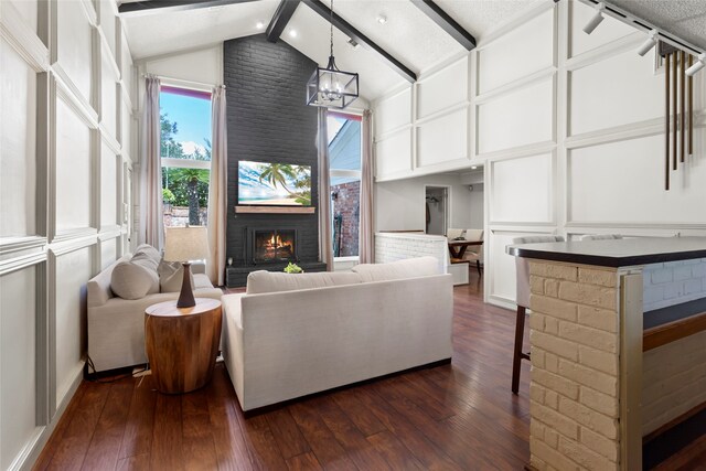 living room featuring a brick fireplace, dark wood-style floors, and a chandelier