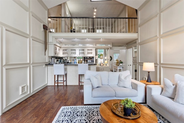 living room featuring a towering ceiling, a decorative wall, and hardwood / wood-style floors